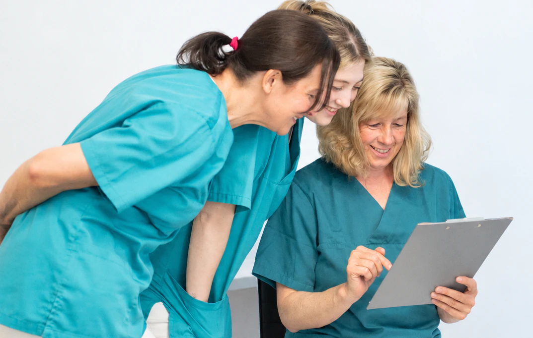 ZFA schauen freundlich auf den Anamnesebogen einer Patientin von DEIN DENTAL Lindau