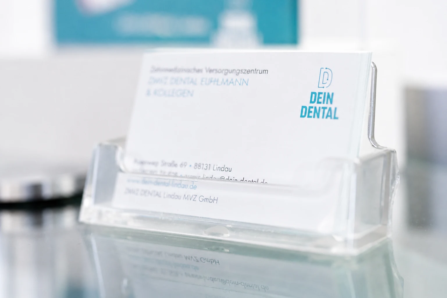 Ein Stapel Visitenkarten von DEIN DENTAL Lindau in einem durchsichtigen Kartenhälter